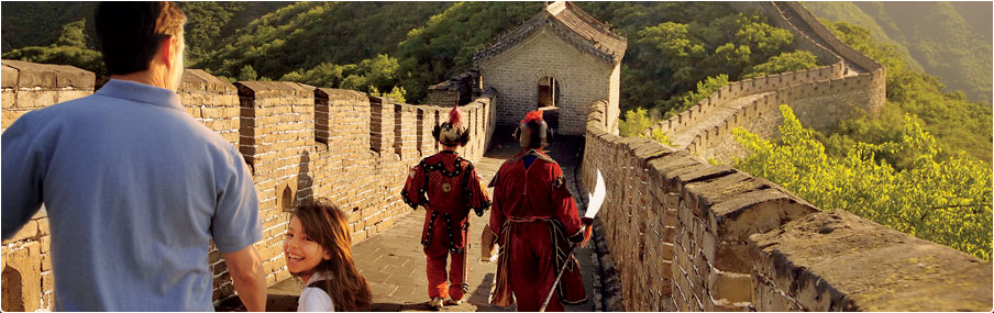 Uniformed guards walk the Great Wall of China as father looks on and a smiling daughter looks back