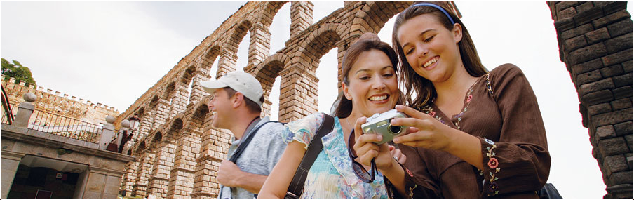 Mom and daughter view vacation shots on her camera while Dad is amazed by the architecture
