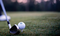 Closeup of golf club and golf ball atop tee