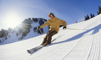 Skier going down a mountain slope on clear blue day